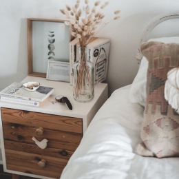 a bed and a nightstand and a vase with flowers