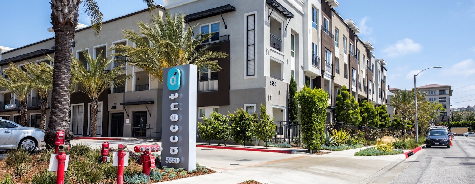 an apartment building with a sign and trees